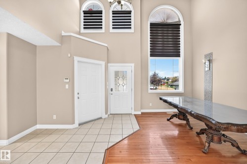 Two-story foyer with a decorative front entry door, arched transom windows, and a combination of tile and wood-finish flooring - 4711 152 Avenue Nw, Edmonton, AB 