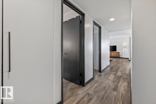 Recessed ceiling lighting, wood-finish flooring, and white walls with contrasting dark trim - #906 12303 Jasper Av Nw, Edmonton, AB 