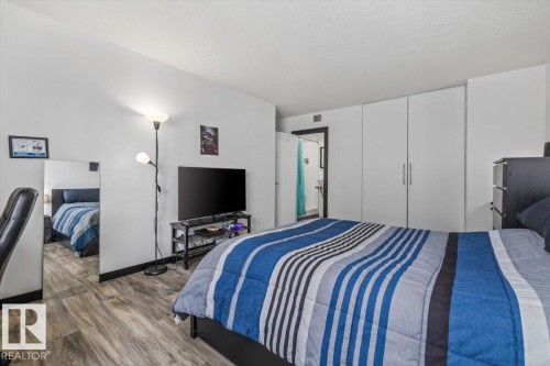 White walls with wood-finish flooring, built-in white cabinetry, and a black-framed doorway - #906 12303 Jasper Av Nw, Edmonton, AB 