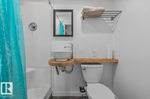 Enclosed shower-tub combination, wall-mounted vessel sink, wood shelf vanity, and a wall-mounted towel rack - #906 12303 Jasper Av Nw, Edmonton, AB 