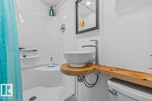 White shower-tub combination with built-in shelving, a vessel sink on a wood-finish vanity, a chrome faucet, and a wall-mounted mirror - #906 12303 Jasper Av Nw, Edmonton, AB 
