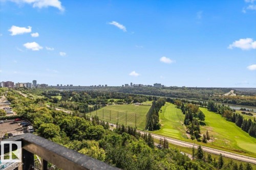 Expansive aerial perspective showcasing manicured grounds with mature tree-lined landscaping, verdant open lawns, and a tree-lined pathway traversing the property - #906 12303 Jasper Av Nw, Edmonton, AB 