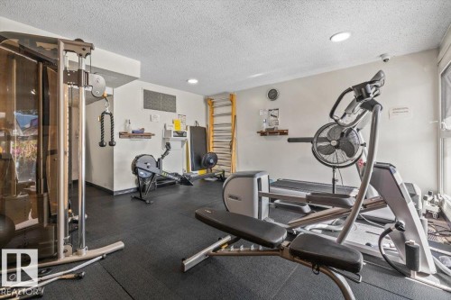 Well-equipped fitness room featuring cushioned flooring, track lighting, and a wall-mounted exercise ladder - #906 12303 Jasper Av Nw, Edmonton, AB 