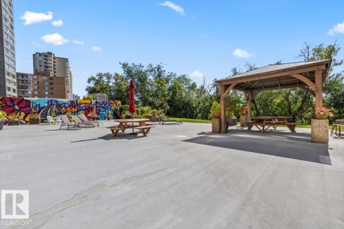 Expansive outdoor paved area with a wooden gazebo and picnic tables - #906 12303 Jasper Av Nw, Edmonton, AB 