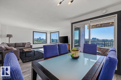 Open-concept living space with wood-finish flooring, multiple windows providing natural light, and a sliding glass door to a private balcony - #906 12303 Jasper Av Nw, Edmonton, AB 
