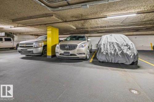 Underground parking area featuring painted concrete flooring, overhead lighting, and painted support columns - #906 12303 Jasper Av Nw, Edmonton, AB 