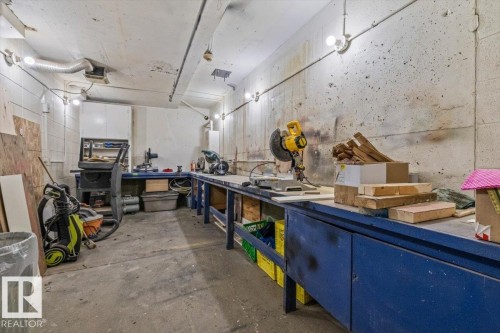 Concrete flooring with exposed conduit lighting and wall-mounted white cabinetry - #906 12303 Jasper Av Nw, Edmonton, AB 