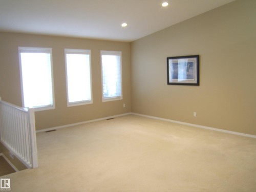 Recessed lighting, warm neutral wall tones, three bright windows, light carpeting, and white railing - 4825 59 Avenue, Vegreville, AB 