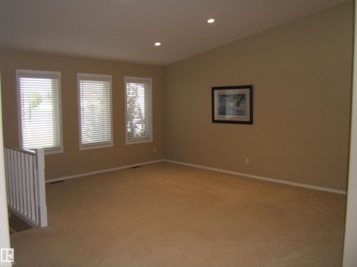 Multiple windows with blinds, recessed ceiling lighting, sloped ceiling, carpeted flooring, and a white baluster railing - 4825 59 Avenue, Vegreville, AB 