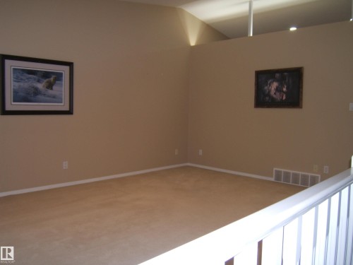 Carpeted room with a vaulted ceiling and neutral wall tones - 4825 59 Avenue, Vegreville, AB 