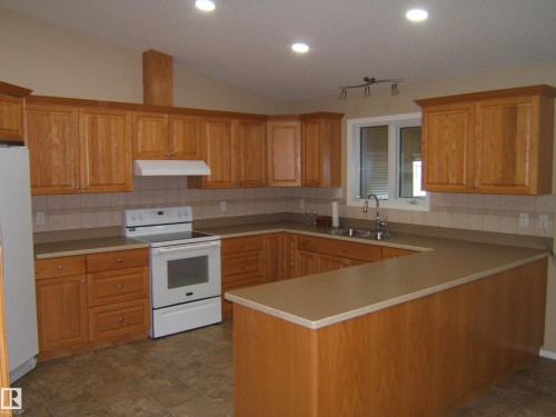 Expansive kitchen featuring light wood cabinetry, U-shaped countertops, a tile backsplash, and recessed lighting - 4825 59 Avenue, Vegreville, AB 