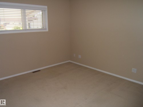Carpeted flooring, neutral wall color, white window trim, and white baseboards - 4825 59 Avenue, Vegreville, AB 