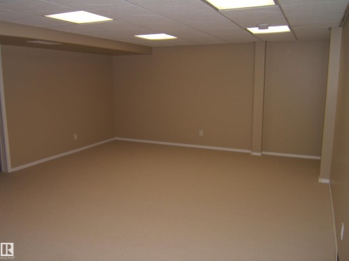 Open room with neutral wall paint, light-colored carpeting, and a dropped ceiling with recessed lighting - 4825 59 Avenue, Vegreville, AB 
