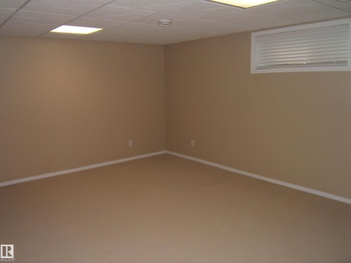 Recessed window with white blinds, neutral wall paint, white trim, drop ceiling with integrated lighting, and carpeted flooring - 4825 59 Avenue, Vegreville, AB 