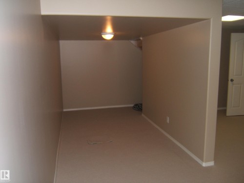Recessed area with wall-mounted lighting, neutral carpeting, and white baseboards - 4825 59 Avenue, Vegreville, AB 