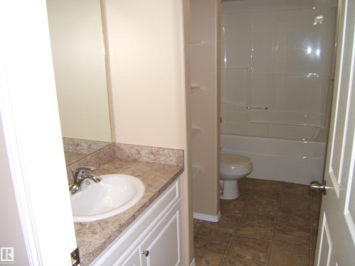 Bathroom vanity with an integrated sink, polished chrome faucet, and a large mirror - 4825 59 Avenue, Vegreville, AB 
