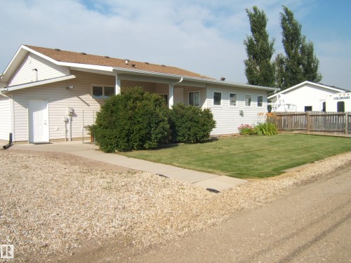Siding exterior with a covered entry, concrete walkway, and a gravel driveway - 4825 59 Avenue, Vegreville, AB 