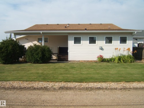 Light-colored horizontal siding, brown shingle roof, established shrubs, and a well-maintained lawn - 4825 59 Avenue, Vegreville, AB 