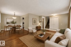 Bright open-concept living area showcasing warm wood-finish flooring throughout, a spacious seating zone with built-in sofa, and a wood coffee table - 