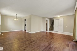 Spacious open-concept living area featuring rich wood-finish flooring throughout, vaulted ceiling with recessed lighting, and neutral wall finishes - 