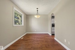Bright, open room featuring rich wood-finish flooring, neutral walls with crisp white trim, and abundant natural light from a large window - 