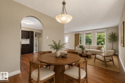 Elegant dining room anchored by a round wood pedestal table and coordinating chairs, with hardwood flooring throughout - 