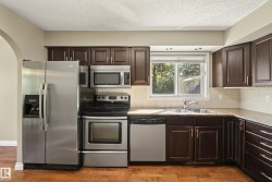 Modern kitchen featuring stainless steel appliances including a side-by-side refrigerator, electric range, microwave, and dishwasher - 