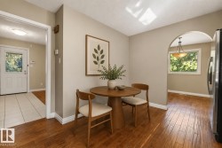 Bright, open kitchen and dining area featuring warm wood-finish flooring, recessed ceiling lighting, and skylights that flood the space with natural light - 