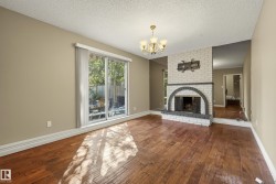 Wood-finish flooring, white brick fireplace with dark arch details, and a sliding glass door - 