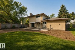 Spacious two-story residence with a generous backyard featuring mature landscaping, manicured lawn, and brick patio - 