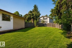 Expansive backyard featuring a meticulously manicured lawn, mature tree canopy providing natural shade, and wooden privacy fencing - 