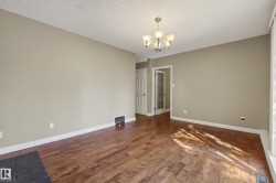 Spacious room featuring rich wood-finish flooring, neutral wall finishes, and abundant natural light from large windows - 