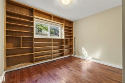 Spacious room featuring custom wood cabinetry with extensive shelving throughout, hardwood flooring, and abundant natural light from dual casement windows - 