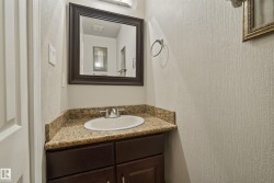 Elegant half bath featuring a dark wood vanity with dual drawers, granite countertop, and round ceramic sink - 