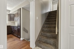 Elegant entry foyer featuring rich wood-finish cabinetry with hardware detail, ceramic tile flooring, recessed ceiling lighting, and a carpeted staircase with neutral wall finishes and white trim throughout - 