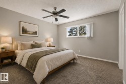 Primary Bedroom featuring neutral wall finishes, carpeted flooring, ceiling fan with integrated lighting, dual nightstands with table lamps, and abundant natural light from multi-pane windows - 