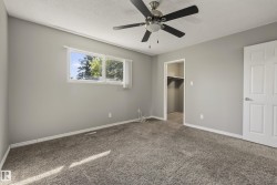 Gray textured carpeting, light gray walls, white trim, ceiling fan with brushed nickel hardware, and a closet with shelving and hanging rods - 
