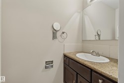 Rectangular wall-mounted mirror, integrated vanity sink, stone-finish countertop, dark wood-finish cabinetry, and brushed nickel faucet - 