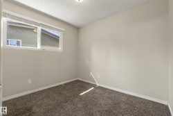 Bright secondary bedroom featuring neutral wall finishes, fresh carpet flooring, and abundant natural light from a transom window - 