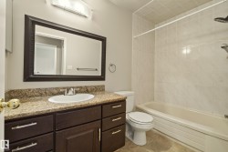 Spa-inspired bathroom featuring a dark wood vanity with dual-sink layout, granite countertop, and brushed nickel hardware - 