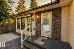 Welcoming front entry featuring a composite deck with dark wood-finish flooring, stone and stucco exterior cladding, recessed lighting, and a white metal handrail - 