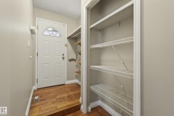 Welcoming entry foyer with solid wood flooring and white six-panel front door featuring a transom window - 