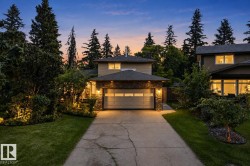 Two-story residence featuring a stone-clad garage, concrete driveway, and a shingled roof - 
