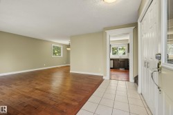 Spacious open-concept living area with rich wood-finish flooring, soft neutral wall tones, and abundant natural light from multiple windows - 