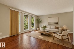 Bright, light-filled living room showcasing gleaming wood-finish flooring, expansive glass doors with golden drapery, and neutral wall finishes - 