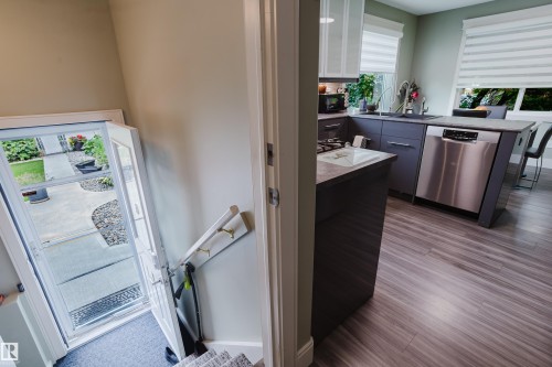Contemporary kitchen featuring dark cabinetry, stainless steel dishwasher, and wood-finish flooring - 14814 104 Avenue Nw, Edmonton, AB - Indoor