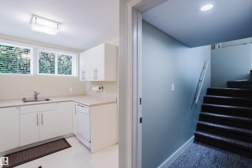 Lower level kitchen featuring white cabinetry, light countertops, and a stainless steel sink - 14814 104 Avenue Nw, Edmonton, AB - Indoor Photo Showing Other Room