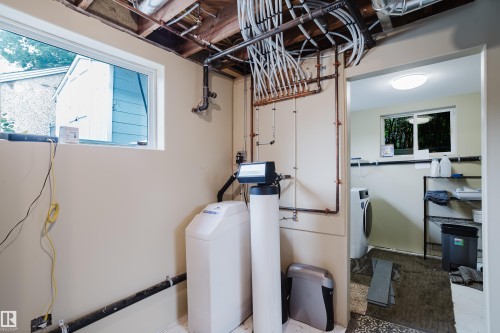 Utility space featuring exposed ceiling joists, comprehensive plumbing, a water filtration system, and a window - 14814 104 Avenue Nw, Edmonton, AB - Indoor Photo Showing Laundry Room