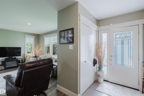 Entryway featuring a decorative white front door with multiple glass panels, an adjacent sidelight, and a built-in closet with bifold doors - 14814 104 Avenue Nw, Edmonton, AB - Indoor