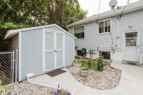 Backyard area featuring a light blue storage shed, concrete pathway, and gravel landscaping - 14814 104 Avenue Nw, Edmonton, AB - Outdoor With Exterior